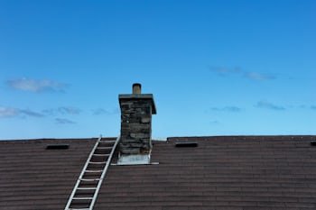 Chimney with a ladder set up for service, similar to homes throughout Euclid, OH